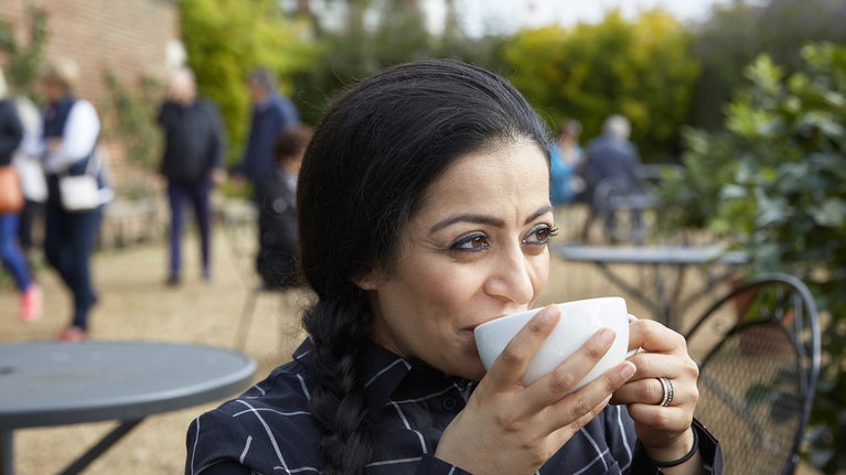 A woman sitting outside a cafe in October at Ham House and Garden, Surrey